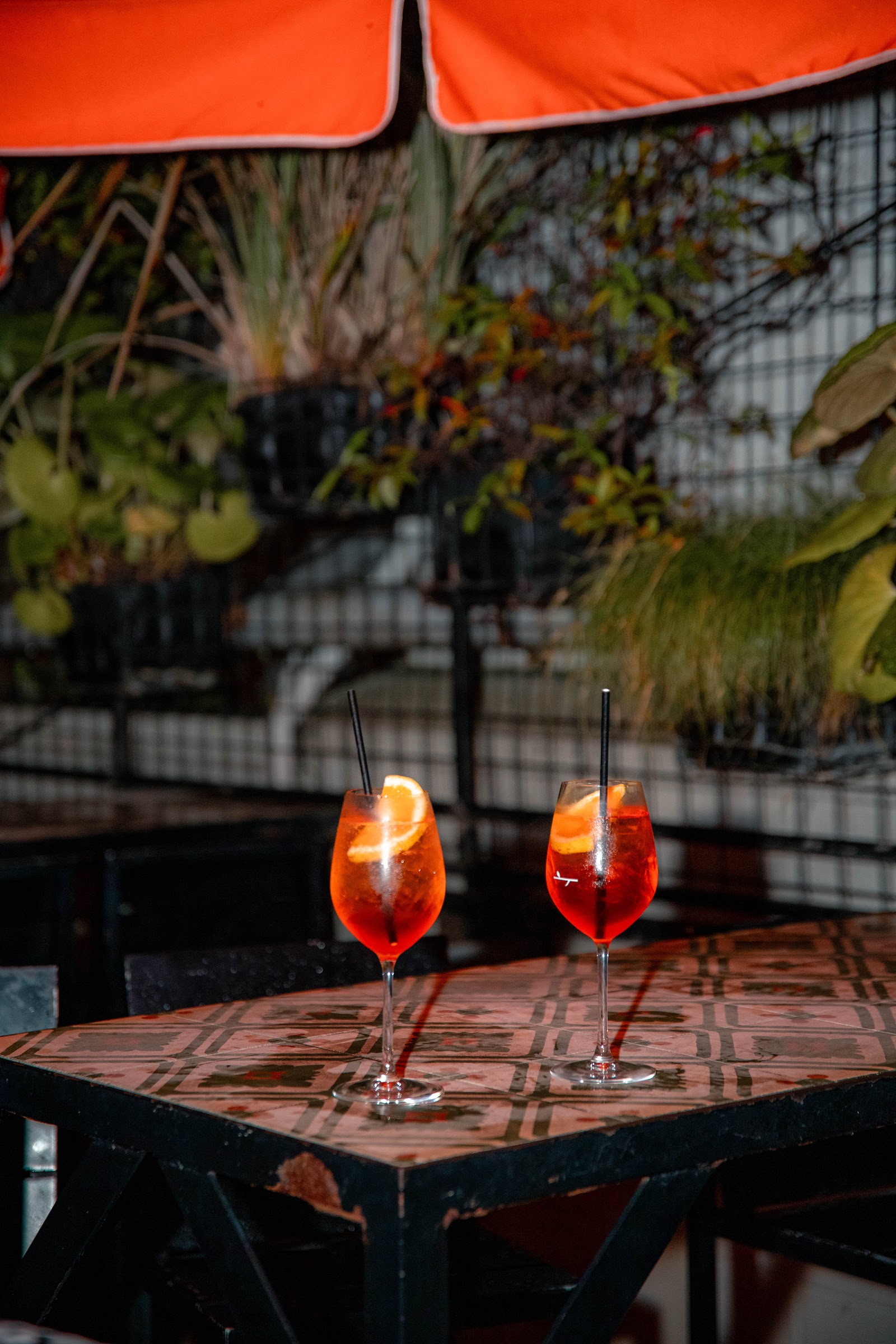 Two spritz cocktails on a tiled table at dusk
