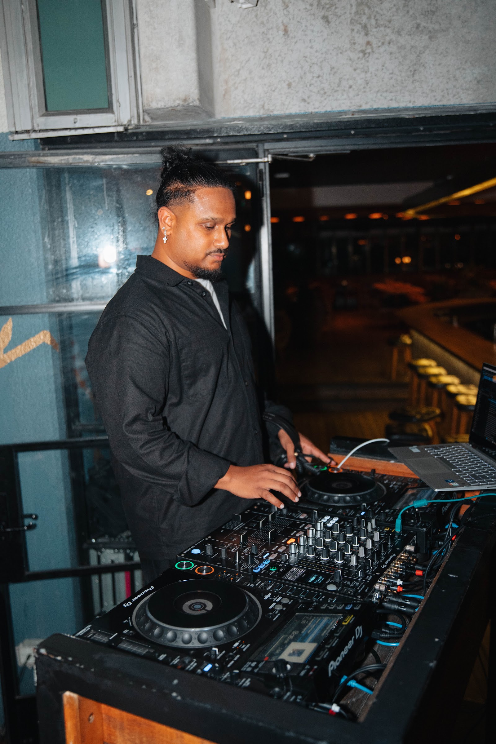 A DJ mixing at the booth with the room behind him